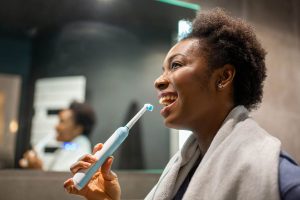 Smiling woman brushing her teeth with an electric toothbrush