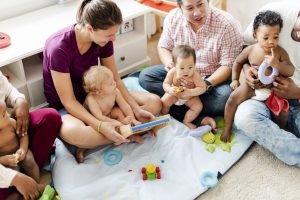 Parents sitting on the floor playing with their babies and toddlers