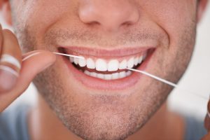 Close-up of a man flossing between his front teeth
