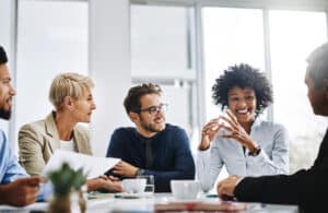 Group of smiling professionals in a meeting, demonstrating the confidence that comes from good dental hygiene at work