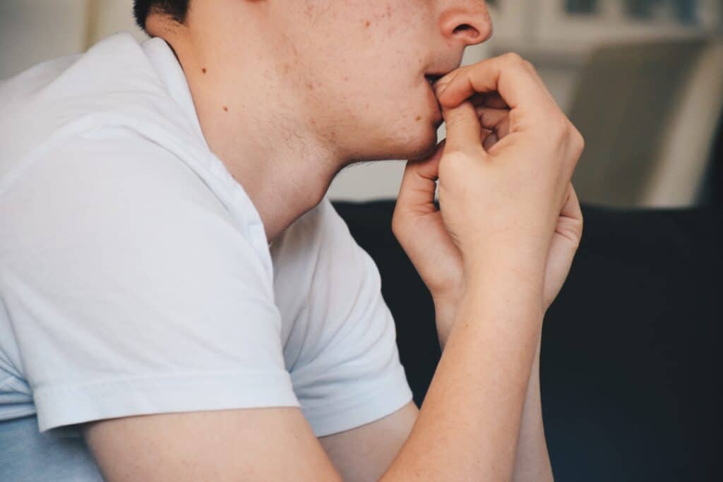 Close-up of person biting nails, a common habit harmful to teeth