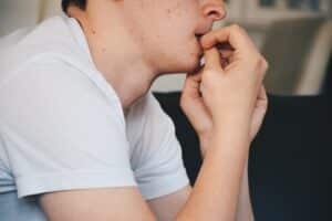 Close-up of person biting nails, a common habit harmful to teeth