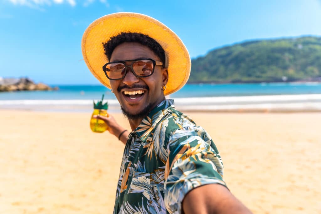 Young adult in summer attire smiling with drink, showing healthy teeth