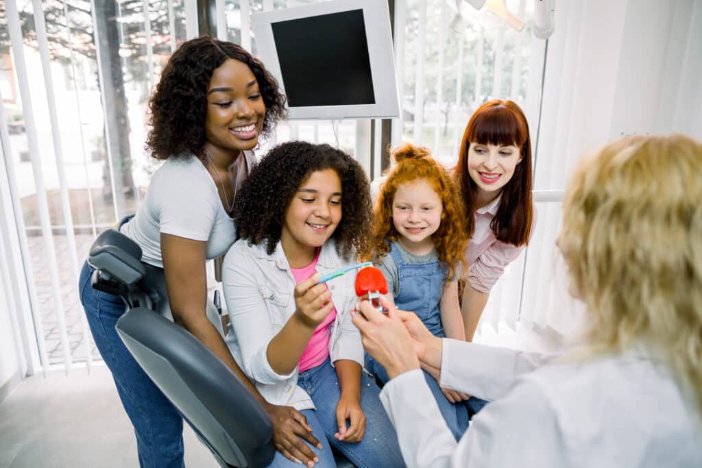Family learning proper tooth brushing technique from dentist in dental clinic