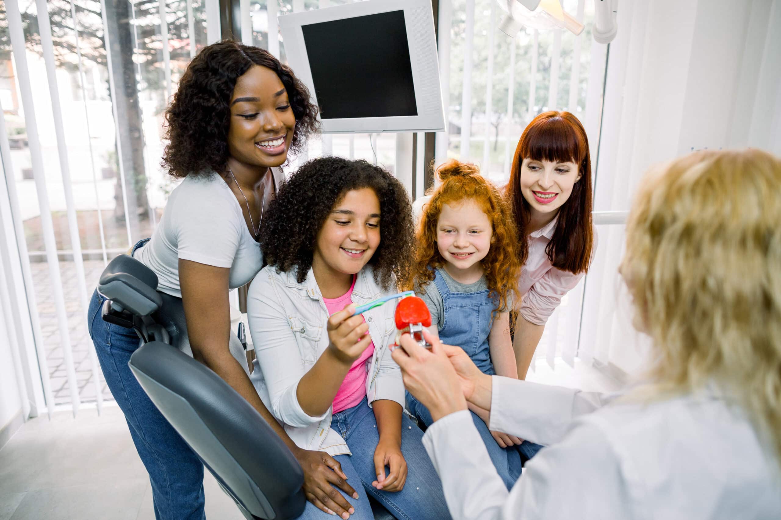 Family learning proper tooth brushing technique from dentist in dental clinic