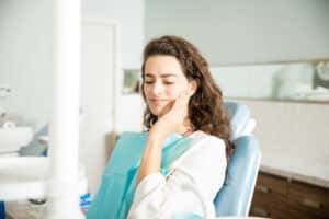 Woman experiencing toothache while sitting in dental chair