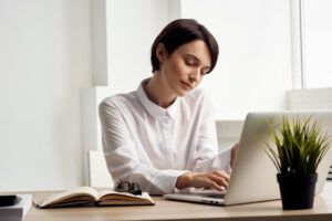 Professional woman working on a laptop at a desk, illustrating screen time habits that may affect oral health