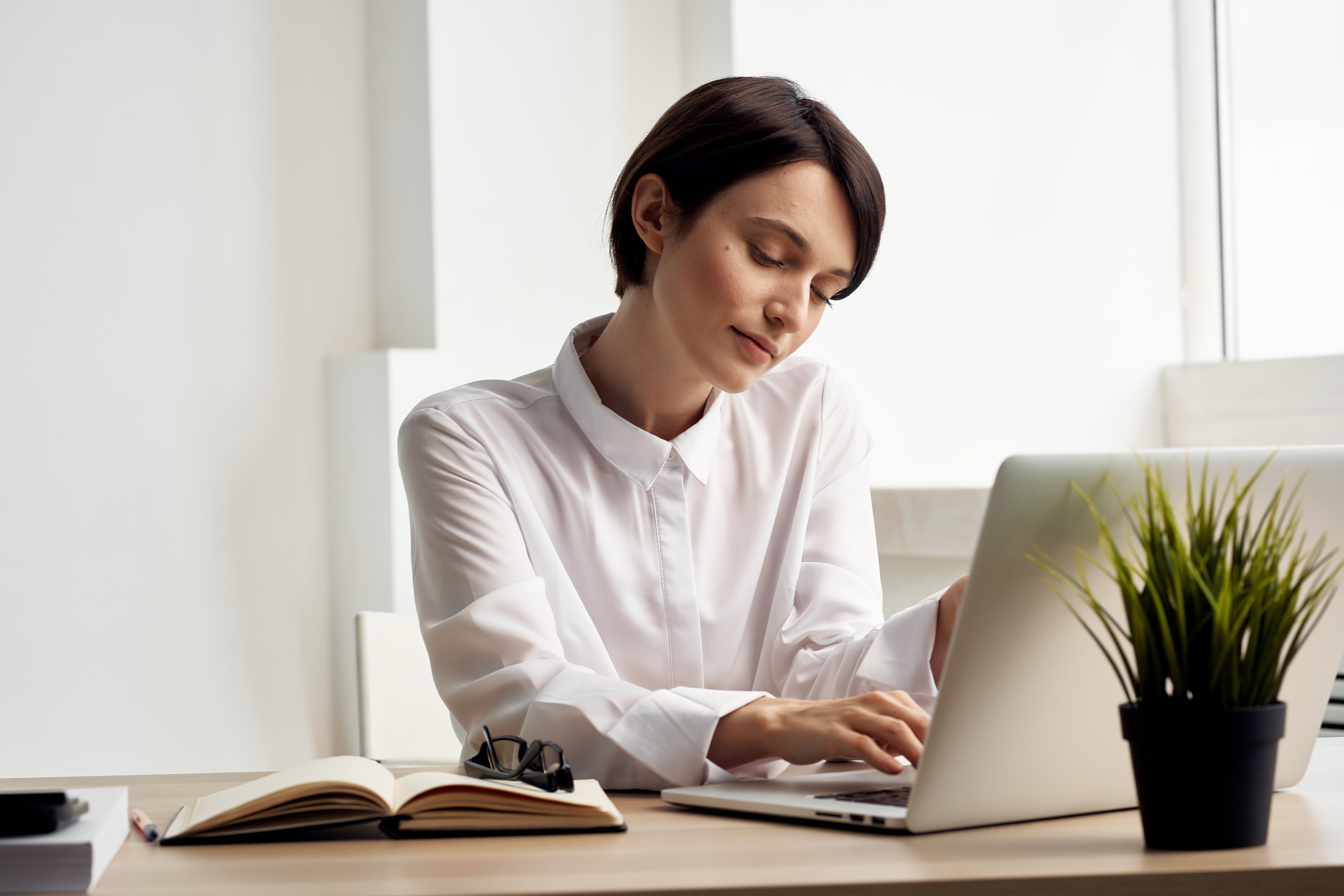 Professional woman working on a laptop at a desk, illustrating screen time habits that may affect oral health
