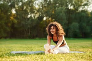Smiling young fitness woman outdoors on a field, representing the connection between fitness trends, healthy lifestyle, and strong oral health.