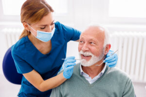A senior patient receiving a dental checkup from a dentist, representing CDCP dental care services in Toronto.