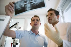 A dentist reviewing a dental X-ray with a patient during a consultation about missing teeth and oral health risks.