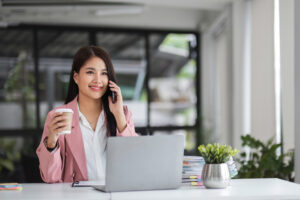 A remote worker drinking coffee while on a phone call, illustrating how work from home habits can affect oral health.