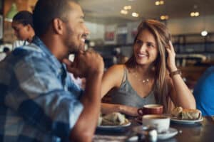 A couple smiling on a first date in a Toronto cafe, highlighting how confidence and a healthy smile influence dating success.