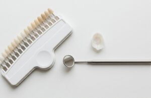 Composite resin shade guide and a porcelain veneer next to a dental mirror, comparing bonding and veneers